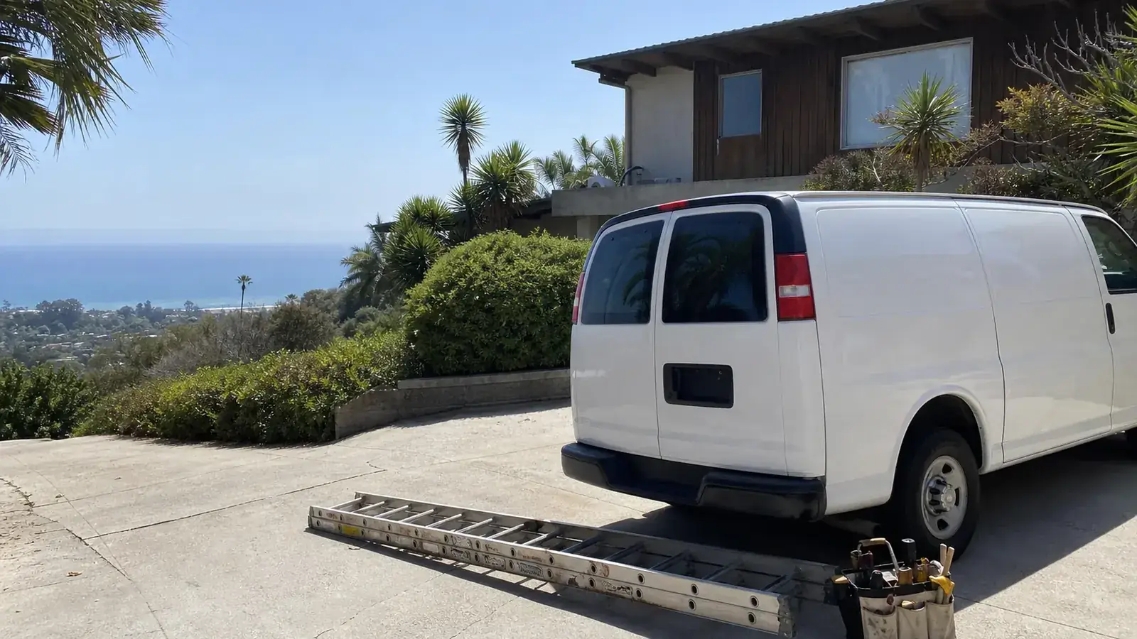 Handyman services in Malibu: handyman work van on a Malibu hillside driveway with a ladder and tool bag, ocean in the distance